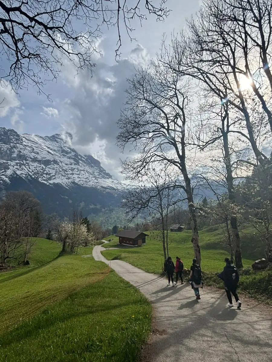 A small group hiking towards the snow-capped Eiger above Grindelwald